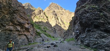 Wanderer durch die schmale Geierschlucht, umgeben von steilen, felsigen Wänden und üppigem Grün in der Umgebung.