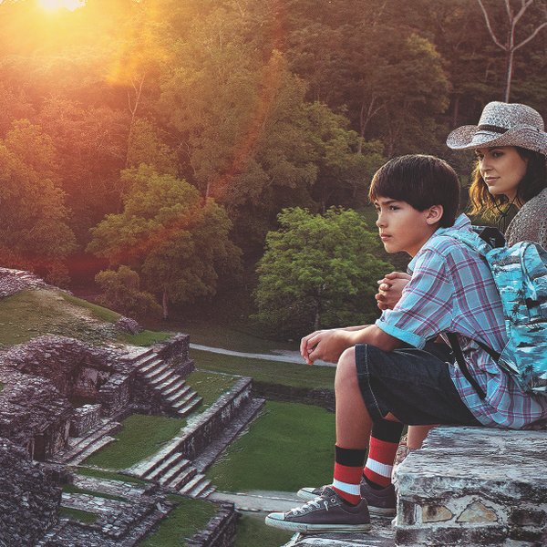 Schwester und Bruder sitzen nebeneinander und schauen auf die geheimnisvollen Ruinen einer Maya-Stätte – Mexiko mit Kindern