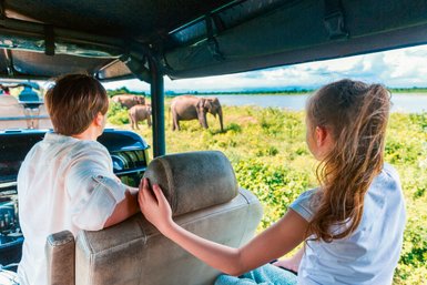 Eine Familie fährt im offenen Jeep durch den Udawalawe Nationalpark auf der Suche nach wilden Tieren – Sri Lanka mit Kindern