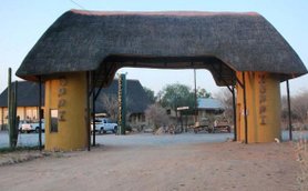 Der Eingangsbereich des Oppi Koppi Restcamps zeigt ein traditionelles Strohdach und farbenfrohe Wände.