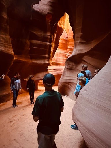 Eine Gruppe von Menschen steht in der beeindruckenden Antelope Canyon, umgeben von rot-orangefarbenen Sandsteinwänden.