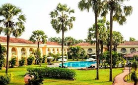 Ein luxuriöses Resort in Goa mit einem einladenden Pool, umgeben von üppigem Grün und hohen Palmen.