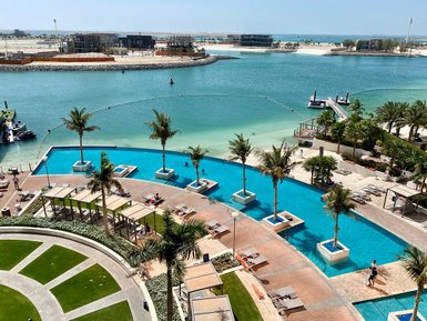 Ein luxuriöser Poolbereich mit Palmen und Liegen, umgeben von klarem Wasser und einem schönen Ausblick auf die Küste.