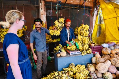 Frau wählt frische Bananen an einem Obststand im Souk von Essaouira – Marokko Reise mit Kindern