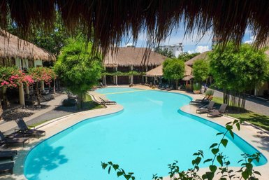 Ein einladender Pool mit klarem Wasser, umgeben von tropischen Pflanzen und gemütlichen Liegen in einem Resort.