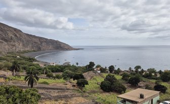 Blick auf die Küste von Tarrafal mit sanften Hügeln, die in die ruhigen Gewässer des Ozeans führen und von Wolken umgeben sind.