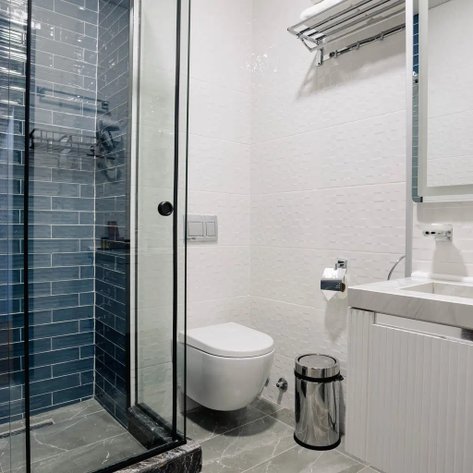 Ein modernes Badezimmer mit einer gläsernen Dusche, eleganten blauen Fliesen und einem weißen Waschbecken.
