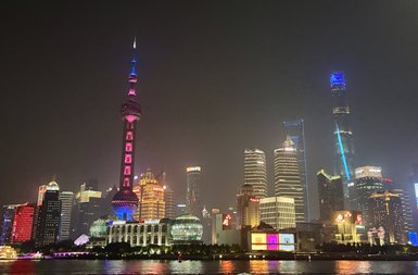 Die beeindruckende Skyline von Shanghai erstrahlt nachts in bunten Lichtern, mit dem ikonischen Oriental Pearl Tower im Vordergrund.