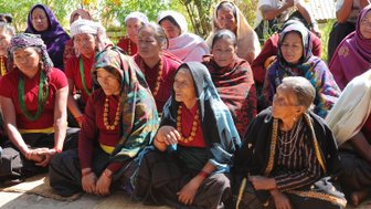 Eine Gruppe von Frauen sitzt zusammen, gekleidet in traditionelle Kleidung, und zeigt eine Atmosphäre der Gemeinschaft und des Austauschs.