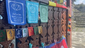 Bunte Gebetsfahnen mit spirituellen Symbolen hängen an einem kunstvoll geschnitzten Holzpaneel in Nepal.