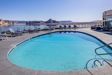 Ein glitzernder Pool mit klarem Wasser, umgeben von Liegen und Blick auf die beeindruckende Landschaft von Lake Powell.