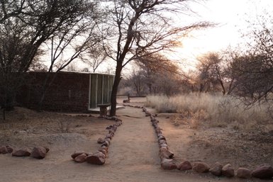 Ein schmaler Weg führt durch das Gelände der Otjiwa Lodge - Namibia mit Jugendlichen