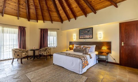 Ein gemütliches Zimmer mit einem großen Bett, Holzdecke und sanften Farben, ideal für Entspannung und Erholung.