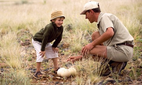 Ein Guide zeigt einem Kind ein Straußenei - Namibia Urlaub mit Kindern