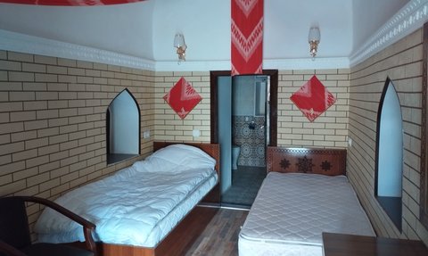 Ein gemütliches Hotelzimmer mit zwei Betten, einem Holzschrank und dekorativen roten Elementen an der Wand.