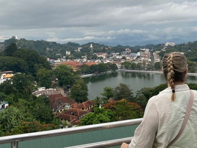 Teenagerin steht auf einem Aussichtspunkt und blickt über die Stadt Kandy – Sri Lanka Reise mit Kindern