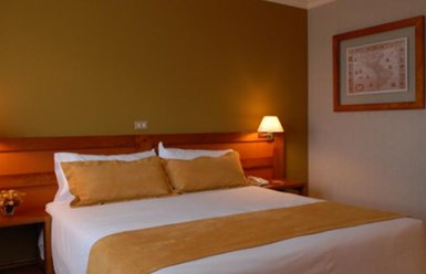 Ein gemütliches Hotelzimmer mit einem großen Bett, das mit beigen Kissen und einer Decke dekoriert ist.