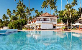 Ein glitzernder Pool umgeben von Palmen und einem eleganten Resort, ideal für entspannende Tage in der Sonne.