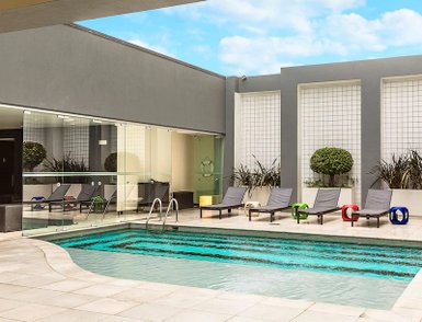 Ein moderner Poolbereich mit Liegen und bunten Schwimmreifen, umgeben von stilvollem, minimalistischem Design.