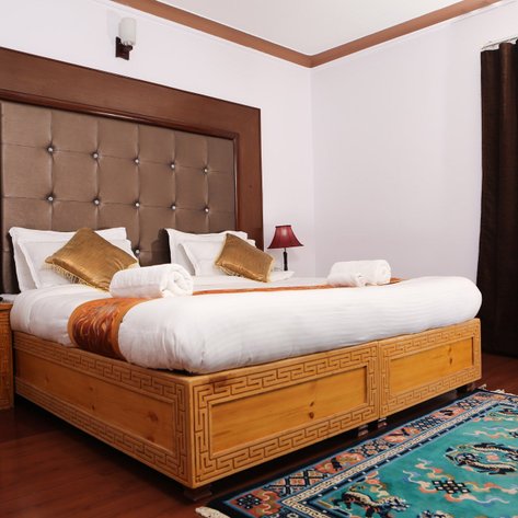 Ein stilvolles Hotelzimmer mit einem großen Bett, eleganten Kissen und einem warmen Holzdesign, das Gemütlichkeit ausstrahlt.