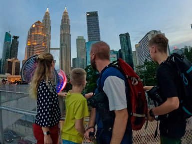 Familie posiert für ein Selfie vor der beleuchteten Skyline von Kuala Lumpur – Malaysia & Borneo Familienreise