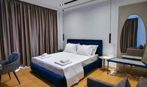 Ein modernes Hotelzimmer mit einem großen, blauen Bett und frischen weißen Bettlaken, das Gemütlichkeit ausstrahlt.