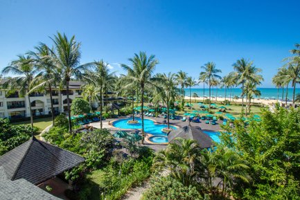 Ein tropisches Resort mit Palmen, einem blauen Pool und Blick auf den Strand, ideal für einen entspannten Urlaub.