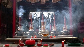 Ein spiritueller Raum mit Räucherstäbchen, Kerzen und einer großen Schüssel, umgeben von Rauch und mystischer Atmosphäre.
