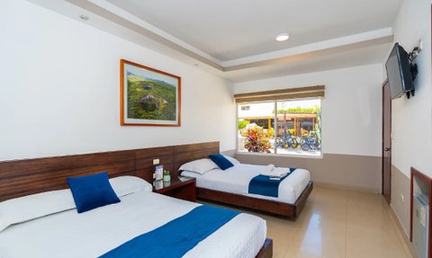 Zwei Einzelbetten mit blauen Akzenten in einem hellen, modernen Hotelzimmer, das viel Tageslicht bietet.