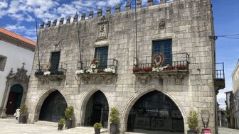 Das alte Rathaus zeigt eine beeindruckende steinerne Fassade mit gotischen Bögen und blühenden Pflanzen auf den Balkonen.