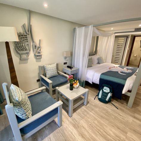 Ein stilvolles Hotelzimmer mit einem großen Bett, dekorativen Kissen und einem kleinen Tisch mit frischen Blumen.