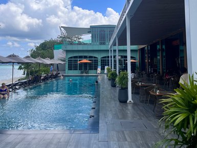 Ein einladender Poolbereich mit Liegen und Sonnenschirmen, umgeben von einem klaren blauen Himmel und weißen Wolken.
