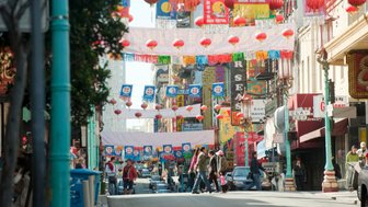 Bunte Laternen und festliche Banner schmücken die Straßen von Chinatown, während Menschen geschäftig umherlaufen.