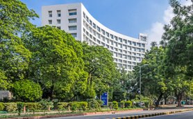 Das moderne Hotel 'The Park' erhebt sich elegant zwischen üppigem Grün und strahlend blauem Himmel in Neu-Delhi.