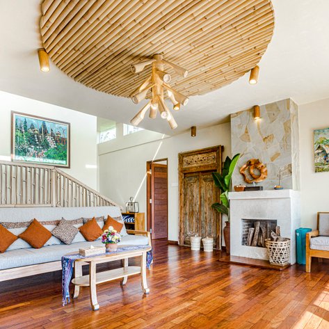 Ein stilvolles Wohnzimmer mit einem großen, runden Bambuslicht und gemütlichen Sofas, die mit bunten Kissen dekoriert sind.