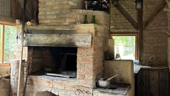 Ein rustikaler Raum mit einem gemauerten Kamin und einer Holzdecke, der eine gemütliche Atmosphäre ausstrahlt.