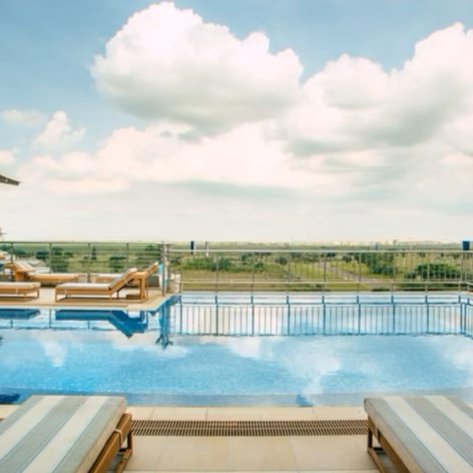 Ein atemberaubender Pool auf dem Dach mit Blick auf die grüne Landschaft und den blauen Himmel, umgeben von Sonnenliegen.
