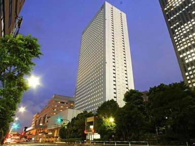 Ein hochmodernes Hotelgebäude erhebt sich majestätisch gegen den Abendhimmel, umgeben von urbaner Landschaft und Bäumen.