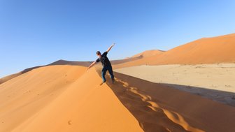 Ein Junge steht auf dem Kamm einer Sanddüne in der Wüste - Namibia Urlaub mit Kindern