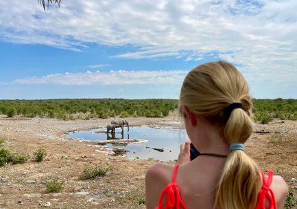Mädchen macht Foto von zwei Elefanten im Wasserloch - Namibia Urlaub mit Kindern