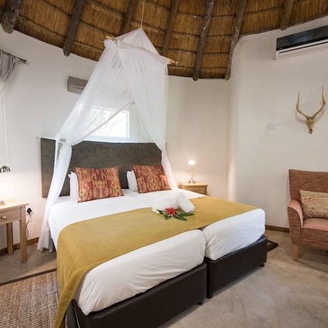 Ein gemütliches Zimmer mit einem Doppelbett, dekoriert mit bunten Kissen und einem frischen Blumenarrangement auf der Bettdecke.