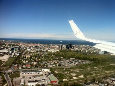 Der Blick aus dem Flugzeug zeigt die Küstenstadt Tallinn mit ihren bunten Gebäuden und dem blauen Wasser im Hintergrund.