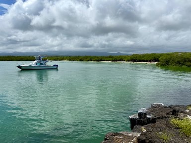 Ein Boot schaukelt sanft auf dem ruhigen Wasser einer Lagune, umgeben von üppigem Grün und dramatischen Wolken.