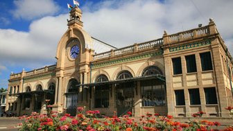 Die beeindruckende Fassade des Bahnhofs in Antananarivo, umgeben von bunten Blumen und unter einem strahlend blauen Himmel.