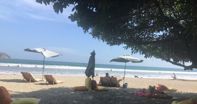 Sonnenliegen und bunte Sonnenschirme am Strand von Sámara – Costa Rica Reise mit Kindern