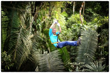 Abenteuerlicher Zipline-Flug eines Mannes über das grüne Blätterdach im tropischen Wald – Mexiko mit Kindern