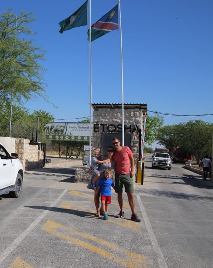 Eine Familie steht vor dem Eingang zum Etosha Nationalpark - Namibia mit Jugendlichen