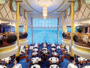 Elegantes Restaurant mit Meerblick, Tische mit weißen Tischdecken und blauen Servietten, stilvolle Einrichtung und Kronleuchter.