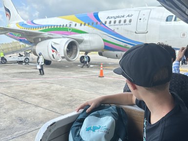Kind mit Rucksack wartet auf Boarding ins Flugzeug - Thailand mit Kindern