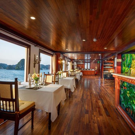 Elegante Restaurant mit Holzboden und Tischen, die auf eine atemberaubende Aussicht auf die Bucht von Ha Long blicken.